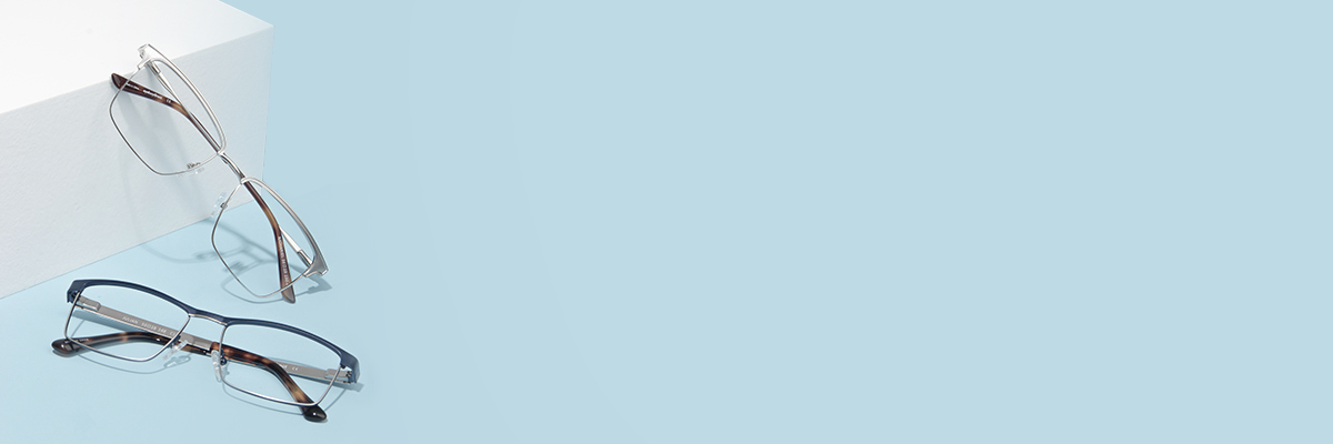 Two pairs of rectangular glasses on a light blue surface