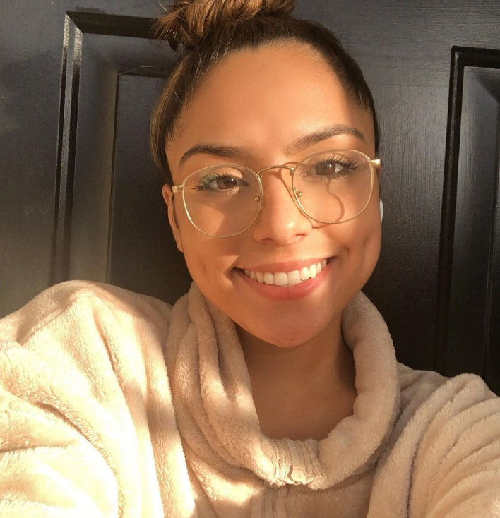 A woman smiling and wearing large eyeglasses